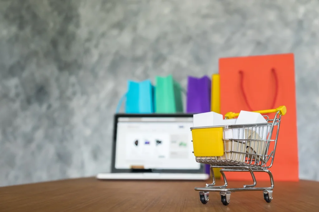 Online shopping on a laptop beside shopping bags